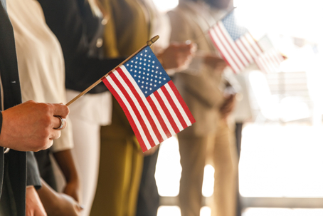 Group of people standing in line holding an American flag