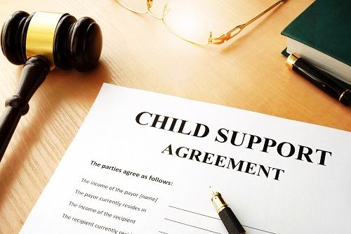 Child support agreement with pens, a gavel, glasses, and a book near by.
