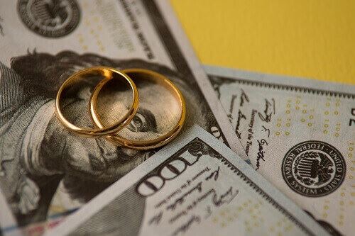 Two gold rings on top of one hundred dollar bills.